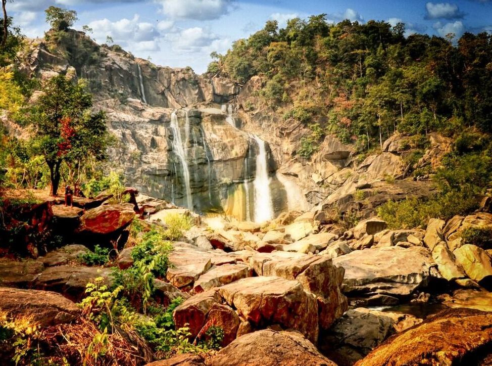 Forested hills and a waterfall spilling over terraced rock in the Netarhat area of Latehar district, Jharkhand.