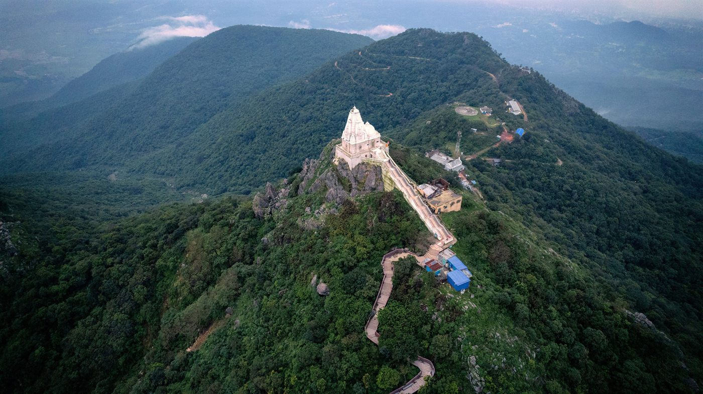 Aerial view of the Shikharji summit temple on Parasnath Hill in Giridih, with the stepped pilgrim path climbing the forested ridge.