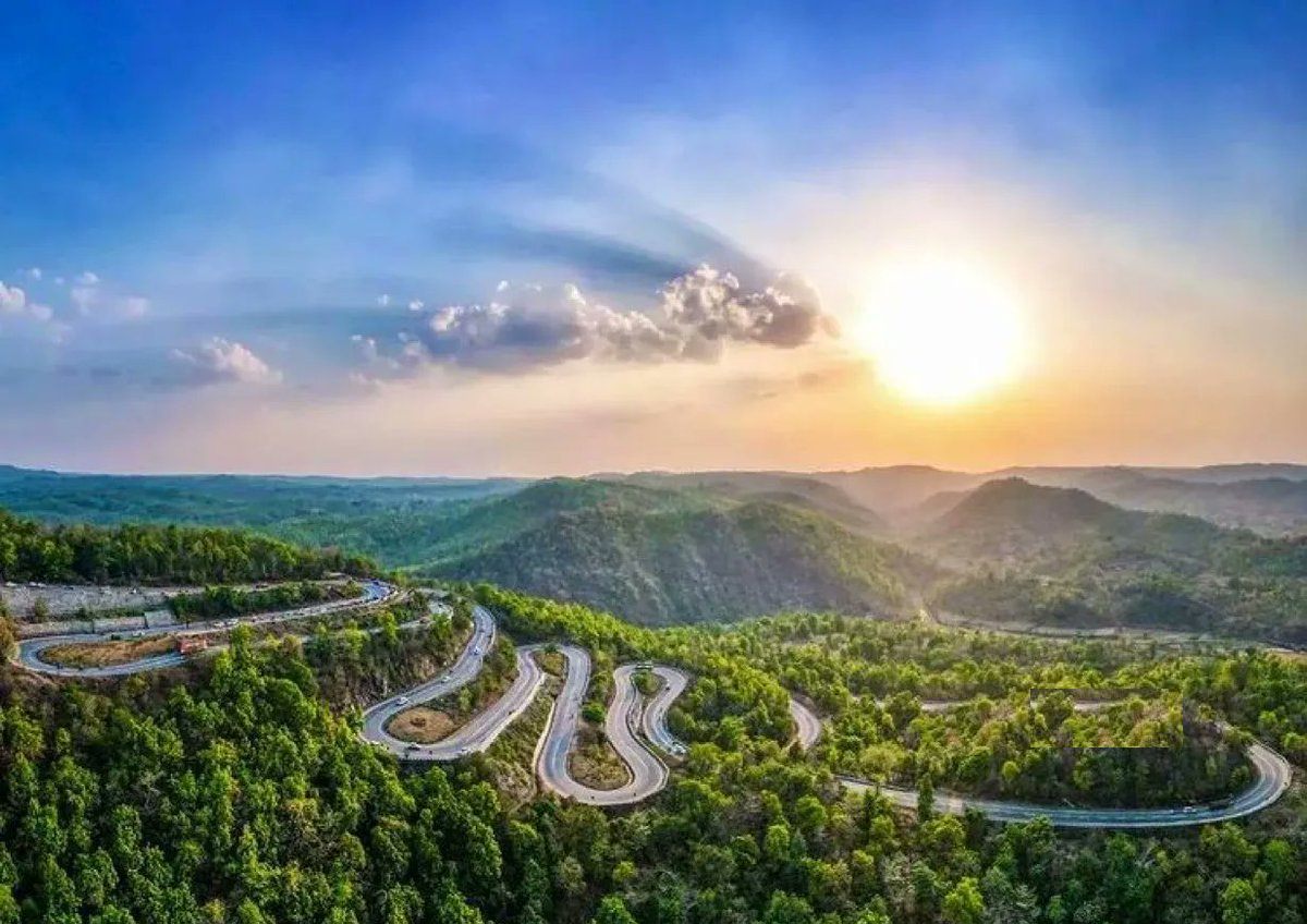 The serpentine ghat road of Patratu Valley winding down through forested hills at sunset in Ramgarh district.